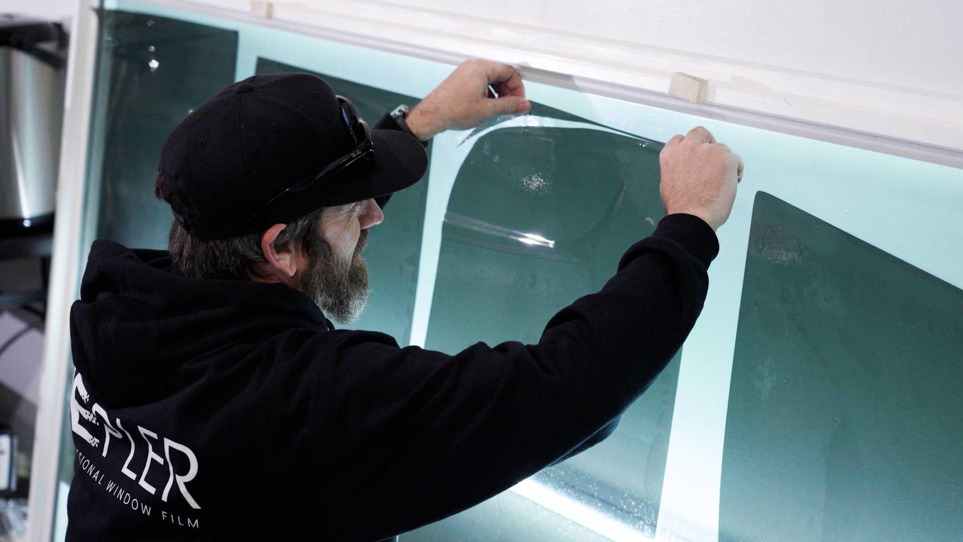 Kepler installer aligning window film on a workshop template wall