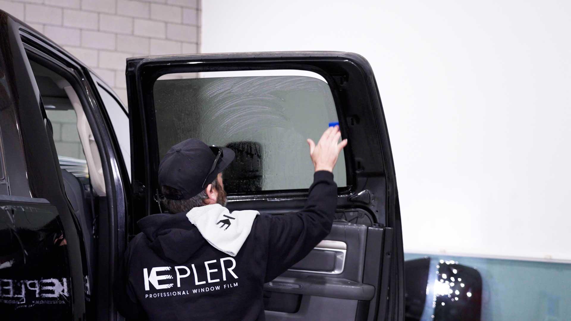Kepler installer smoothing film on a vehicle door window