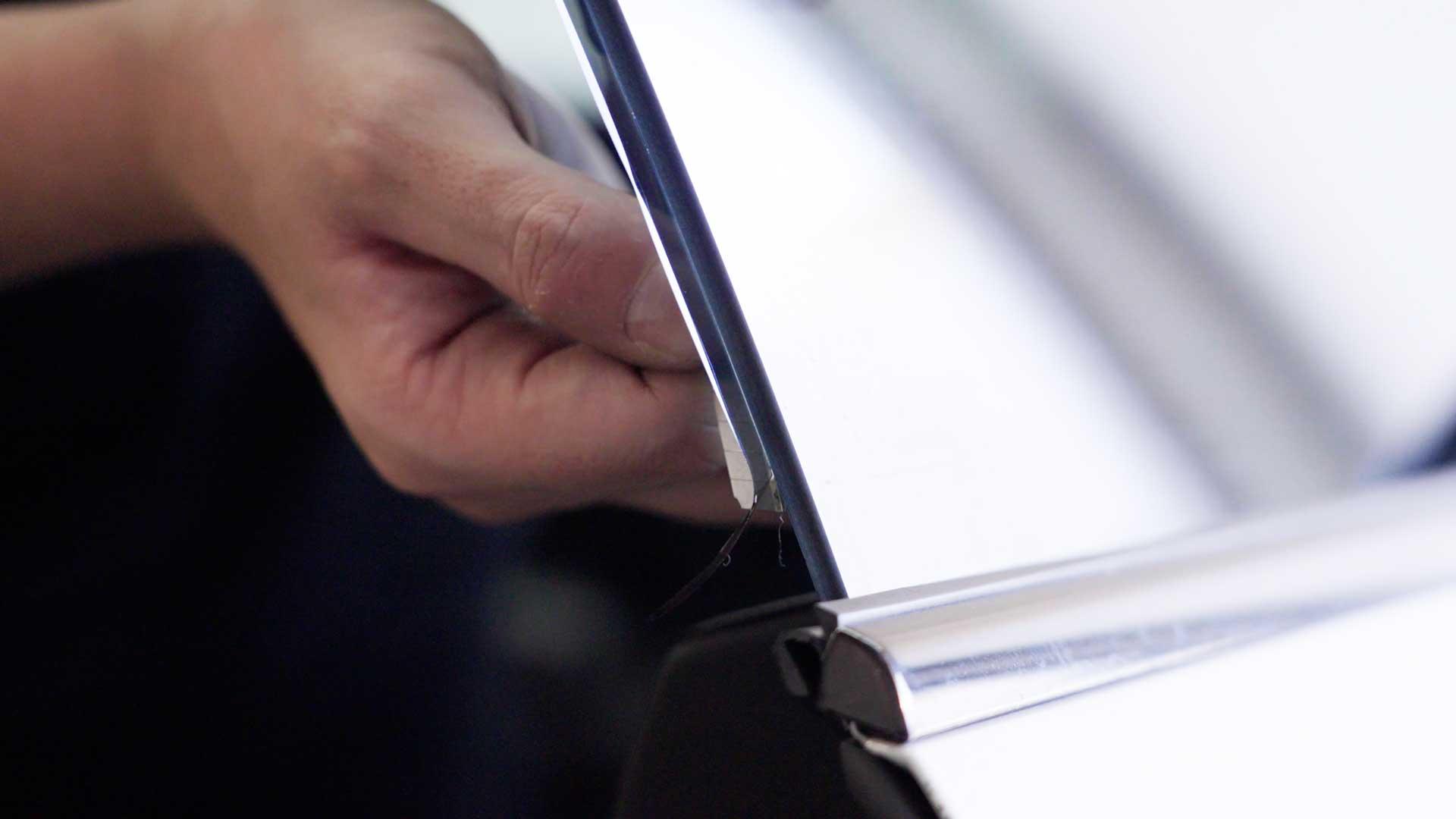 Close-up of Kepler installer trimming film along a vehicle window edge