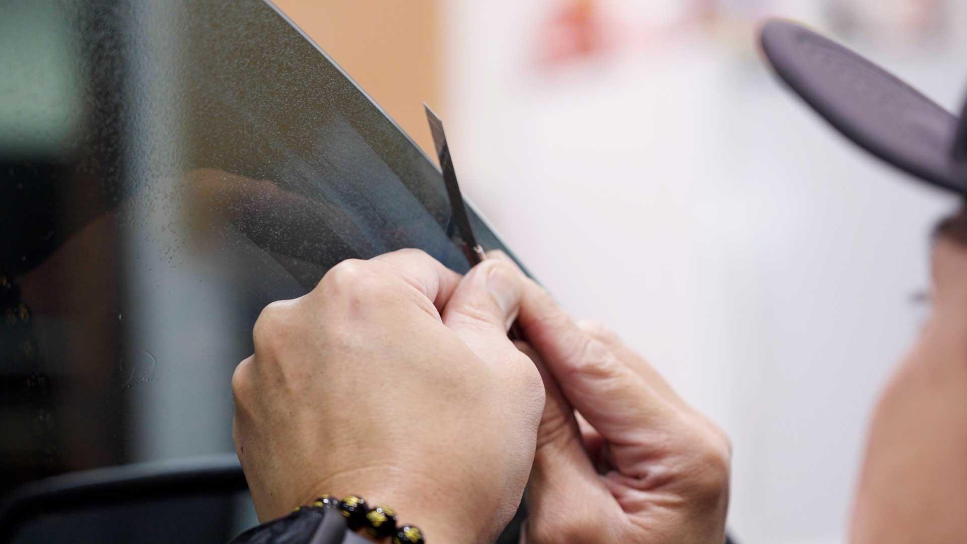 Close-up of precise Kepler window film trimming by hand
