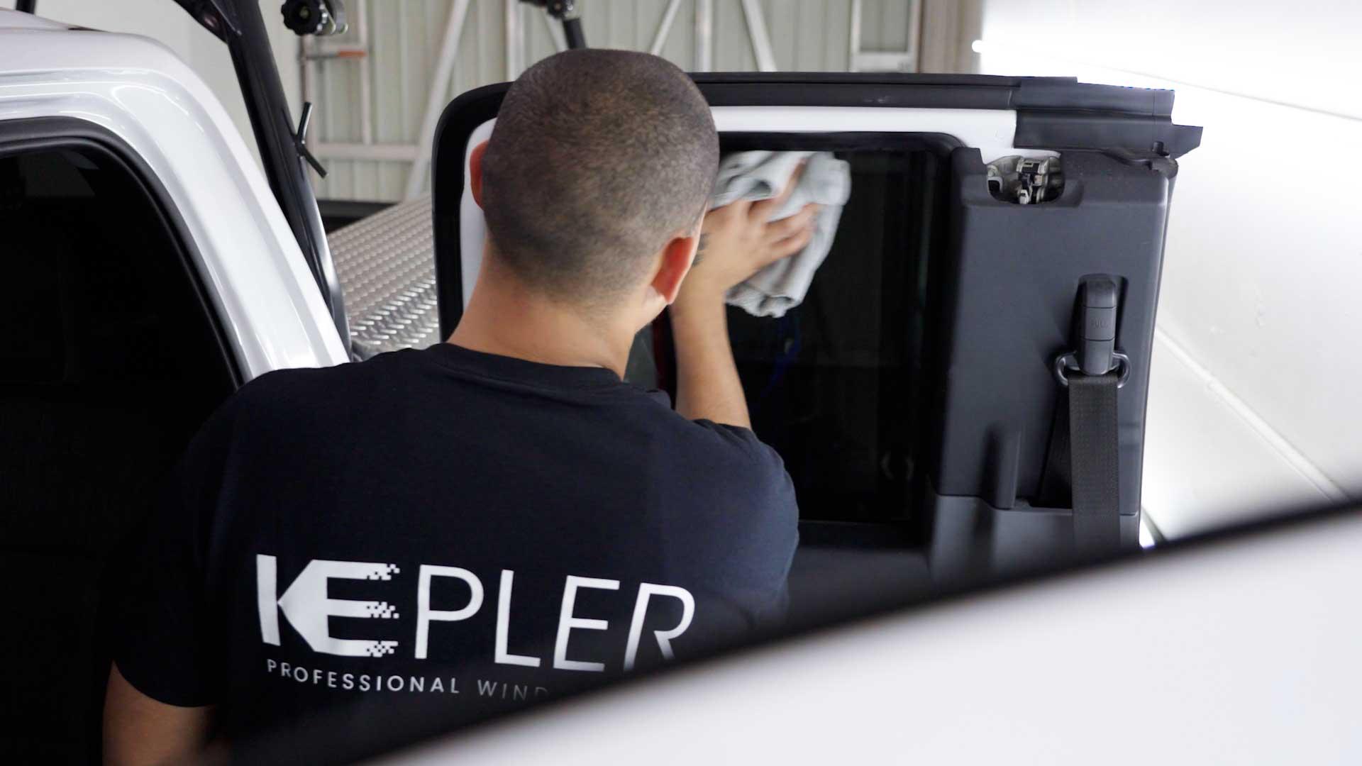 Kepler installer post-cleaning vehicle door glass after tint installation