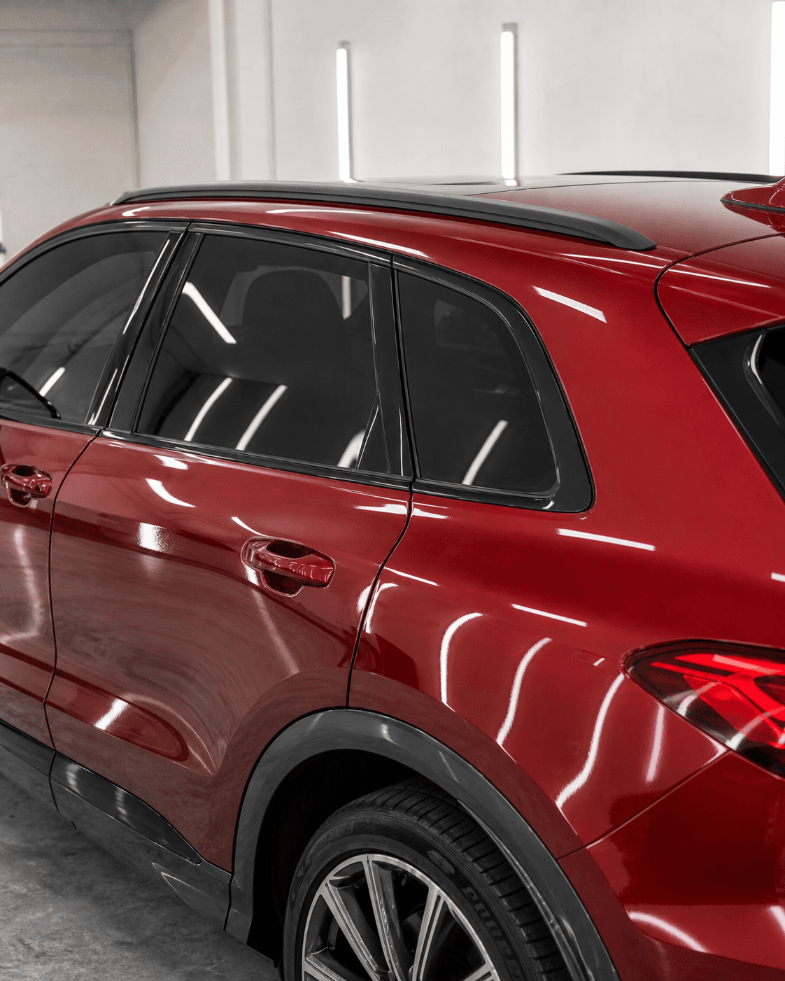 Red 2026 Audi Q5-style SUV with reflective black tinted side windows in a white workshop