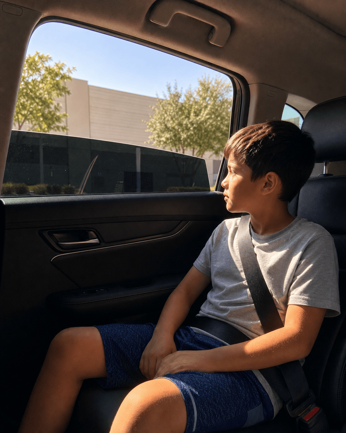 Child passenger in a car with sunlight softened by a half-lowered tinted window