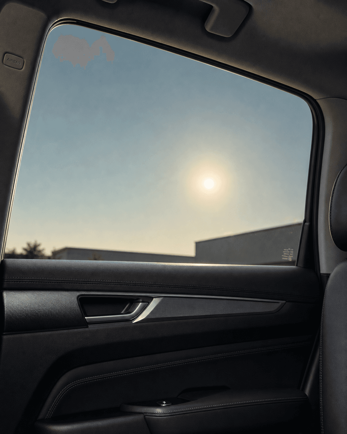Soft sun viewed through a lightly tinted side window in a modern vehicle